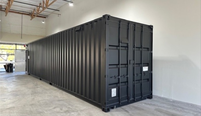 A black 40' Groundhog mobile shooting range container setup inside a warehouse facility.