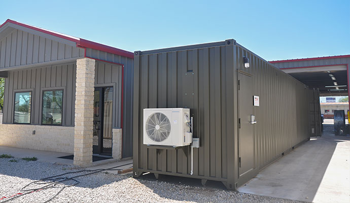 Containerized modular shooting range installed outdoors next to a commercial building