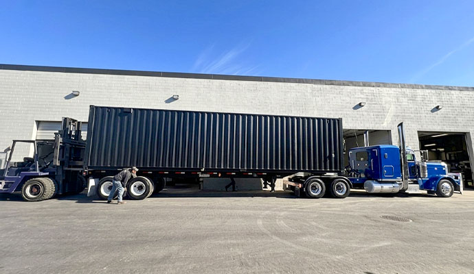Semi truck hauling black container unit