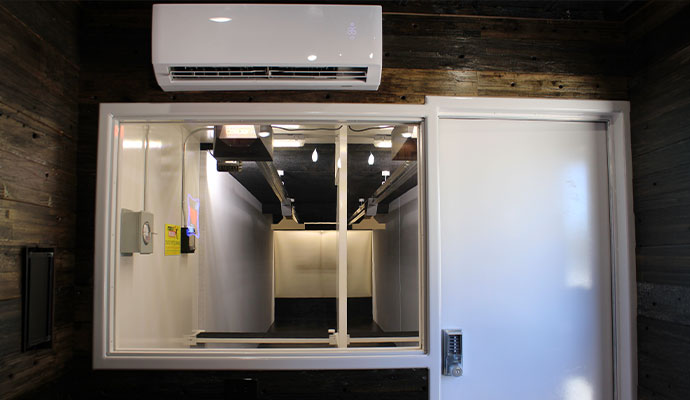 Ballistic entry door with keypad lock, observation window, and mini-split AC unit on an indoor shooting range