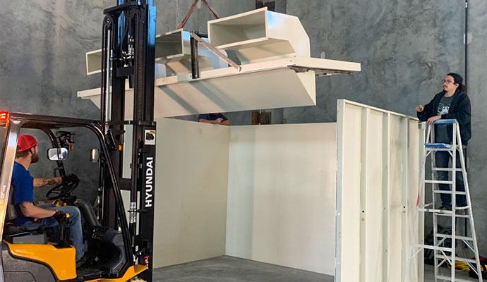 Technicians using a forklift to assemble modular shooting range at facility